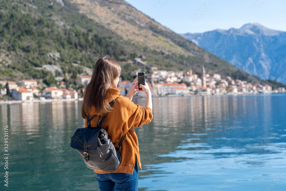 Woman taking photos with smartphone. Travel concept. Montenegro. Kotor