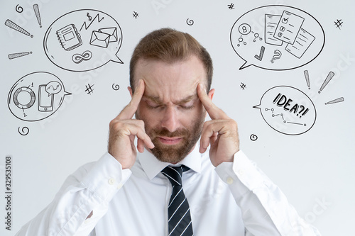 Businessman touching temples with hand drawn business sketches. Man concentrating. Contemplation concept. Isolated front view on background with icons.