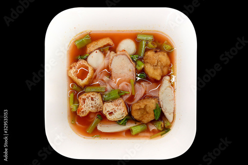 Pink seafood flat noodles, Spicy lemongrass flavored soup with pork, fish ball on Black background.