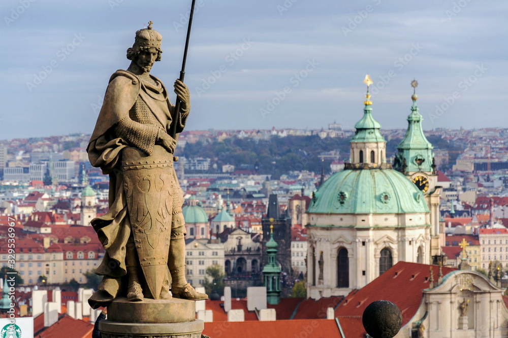 St. Wenceslas Statue in front of the Prague castle, city skyline wit St. Nicholas Church in background, sunny day