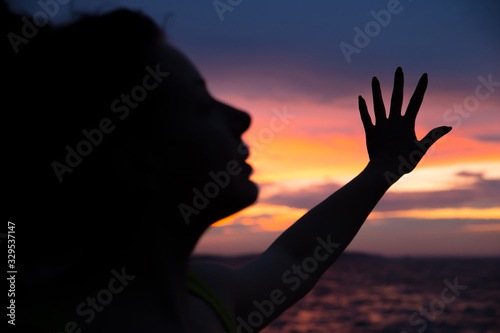 Dark silhouette of a woman on a background of a beautiful sunset sky. Ocean, sunset, man’s power.