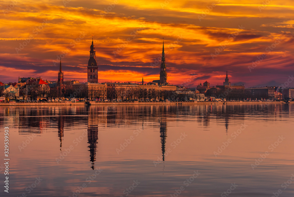 Obraz premium Cityscape of Riga Latvia with Reflections on a Quiet Still River at Sunset
