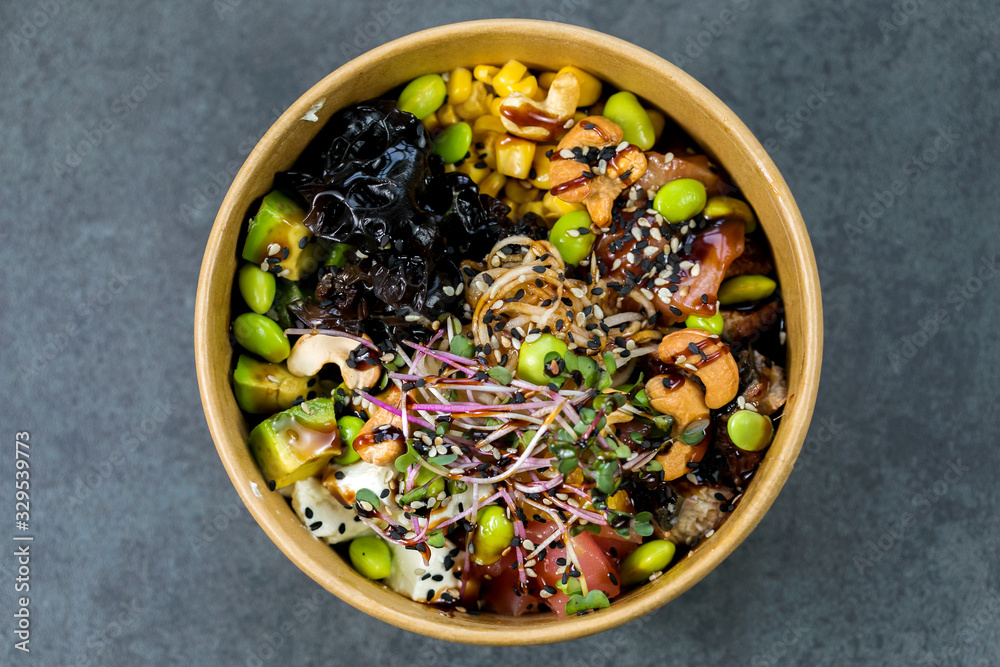 Poke bowl with salmon, guinoa, vegetables, friut and tofu on dark background Poke bowl with salmon, guinoa, vegetables, friut and tofu on dark background
