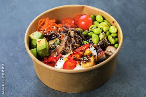 Poke bowl with salmon, guinoa, vegetables, friut and tofu on dark background