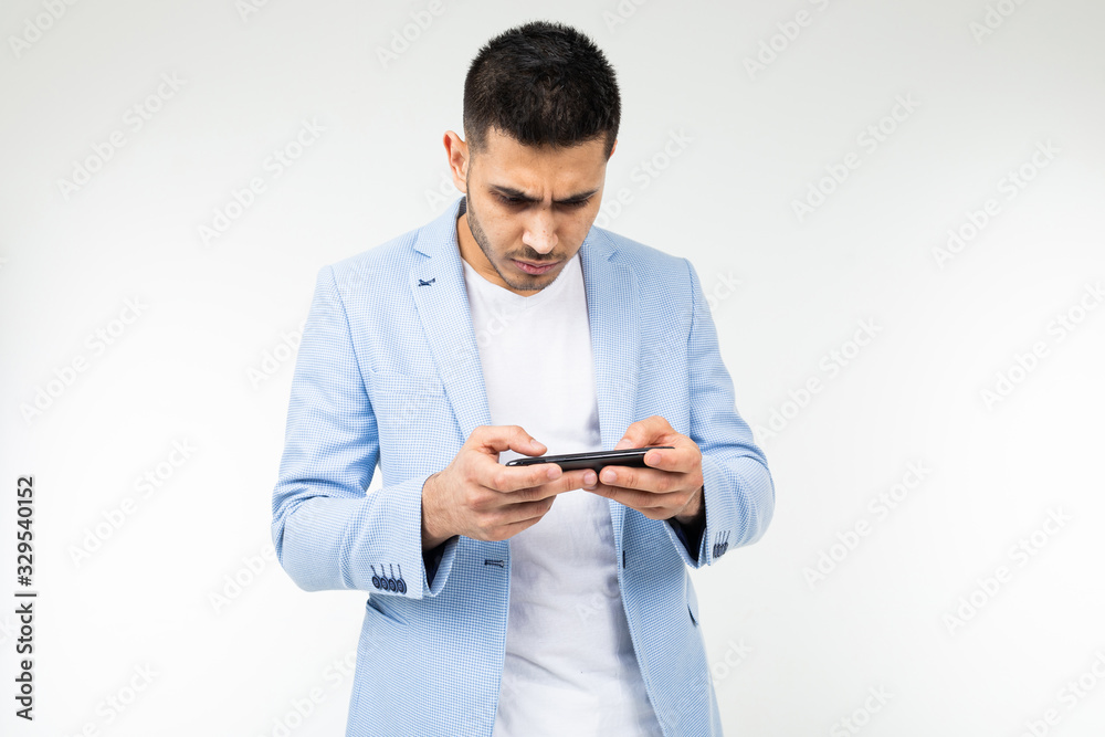 portrait of a happy man in a blue jacket playing a game on a smartphone in a horizontal position