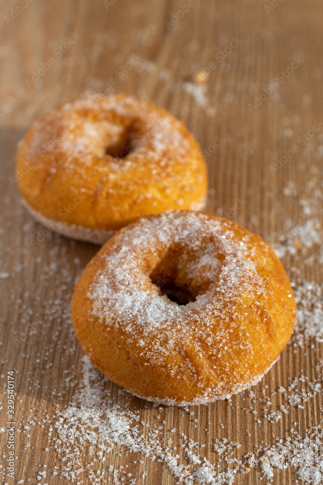 Top view of two donuts with sugar on wooden table in vertical with copy space