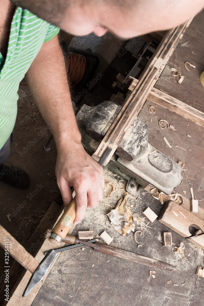 Male carpenter working on old wood in a retro vintage workshop.