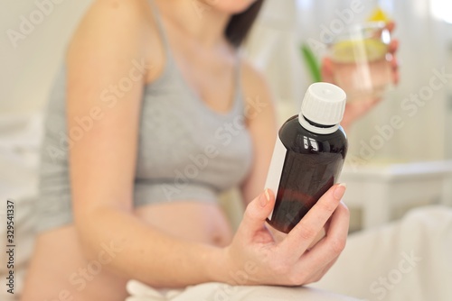 Young pregnant woman holding soluble medicine in her hand, vitamins