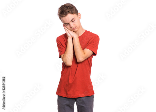 Portrait of teen boy sleeping tired or dreaming posing with hands together while smiling with closed eyes. Cute young caucasian teenager isolated on white background. Happy child.