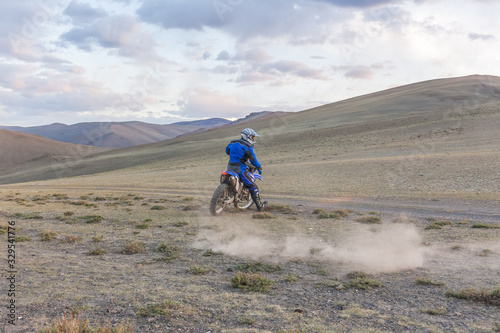 Man riding a motorcross bike in the steppes of Mongolia, on the hills of Mongolia © Tatiana