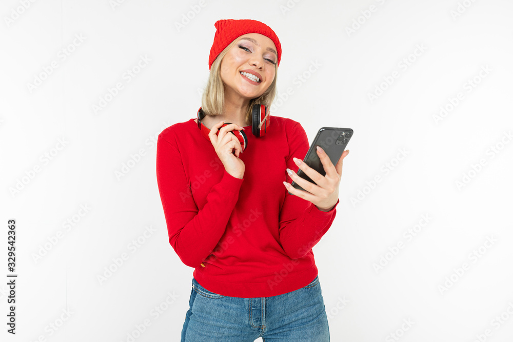 charming smiling young woman in red clothes with headphones and a phone on a white studio background charming smiling young woman in red clothes with headphones and a phone on a white studio background