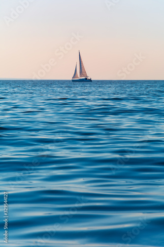 Sailboat in the sea in the evening sunlight. Luxury summer adventure or active vacation concept. Copy space