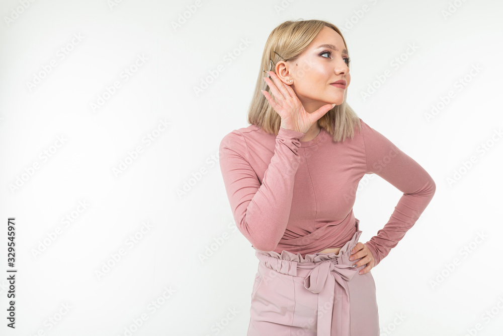 girl with blond hairstyle holds hand by ear eavesdropping conversation on white background with copy space girl with blond hairstyle holds hand by ear eavesdropping conversation on white background with copy space
