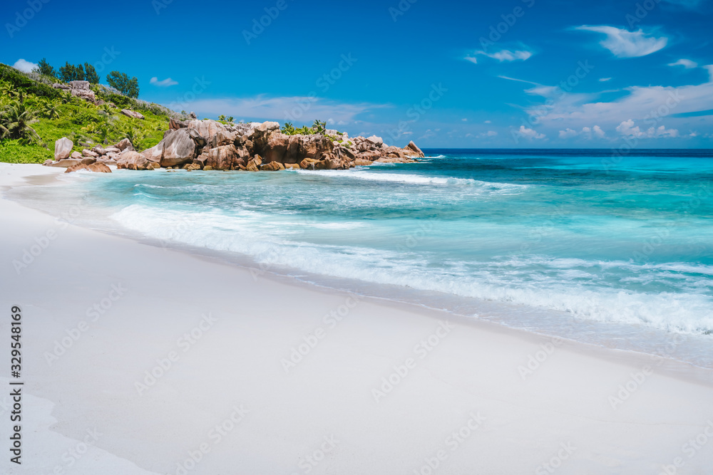 Ocean waves, pristine blue color lagoon and granite rocks on Anse Coco beach, La Digue Island, Seychelles