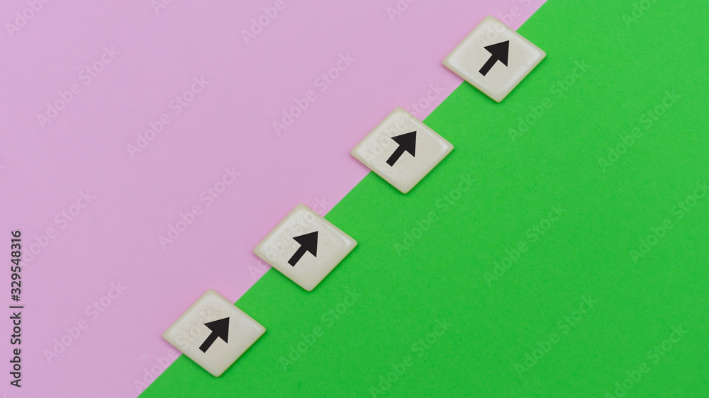 Green and pink background with tile block arrows for concept of growth, goal setting, progress and achievement in business or education.