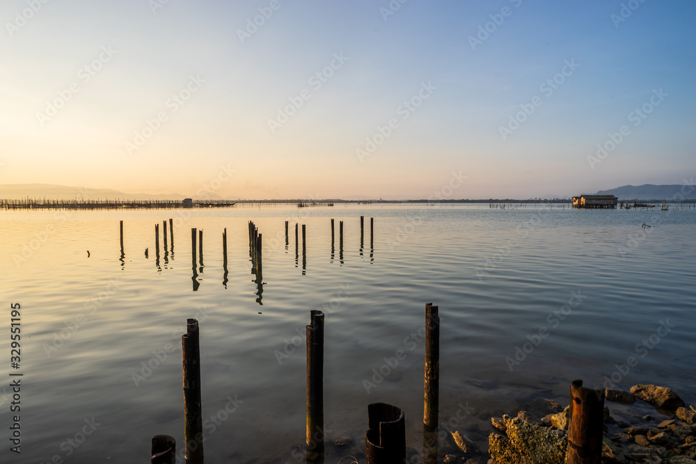 View of the lake with small fishing hut in the middle, left over pole from pier and beautiful clear morning sky.