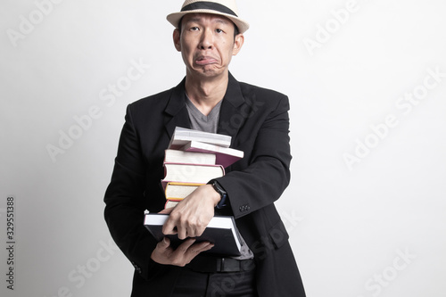 Unhappy adult Asian man  studying  with may books.