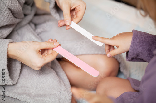 Girl makes manicure mother, at home in bed