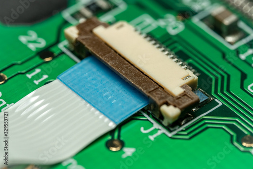 Macro photo of a flat ribbon cable and connector on a green printed circuit board (PCB)
