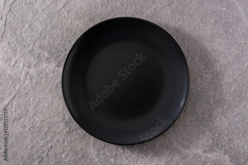 Empty black plate on gray background top view