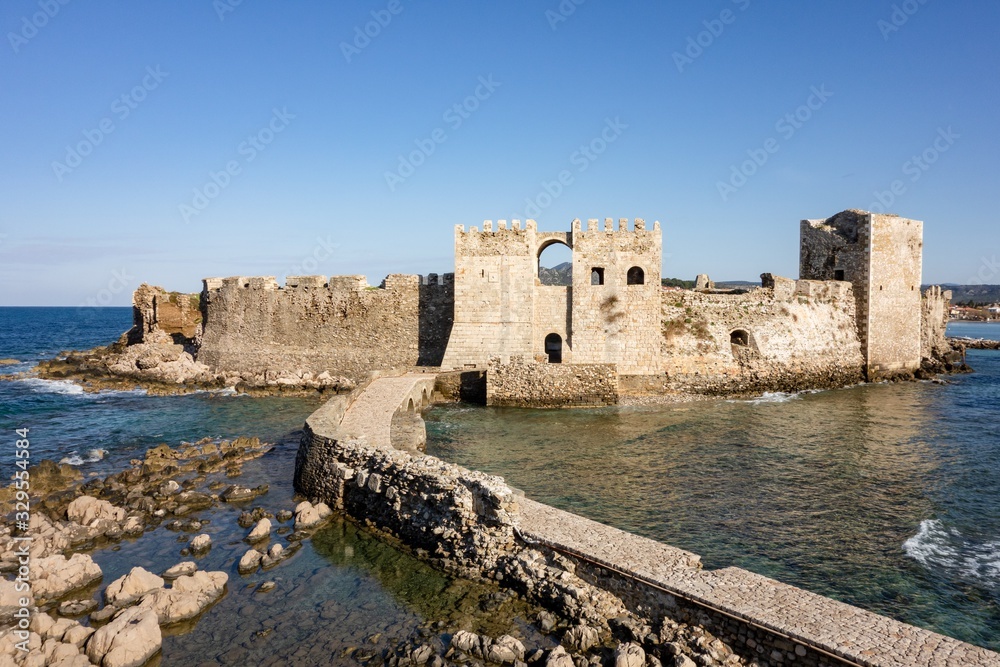 Methoni Castle with a stone bridge during early sunny morning with water sea waves in Greece