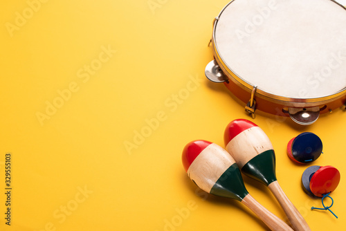 Wooden colorful maracas with tambourine and castanets on yellow background photo