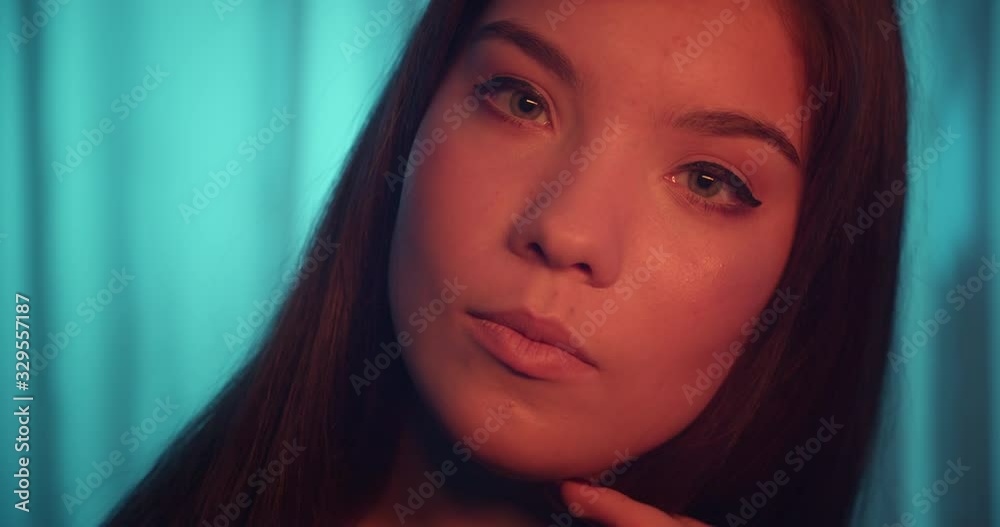 Close-up eyes Caucasian young girl portrait smile orange complexion flirt blue background Close-up eyes Caucasian young girl portrait smile orange complexion flirt blue background