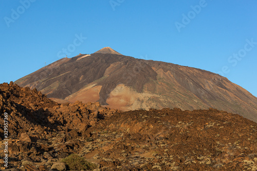 Majestic red volcanic terrain in the Teide national park with Teide Mount on the blue sky background in Tenerife  Canary Islands  Spain
