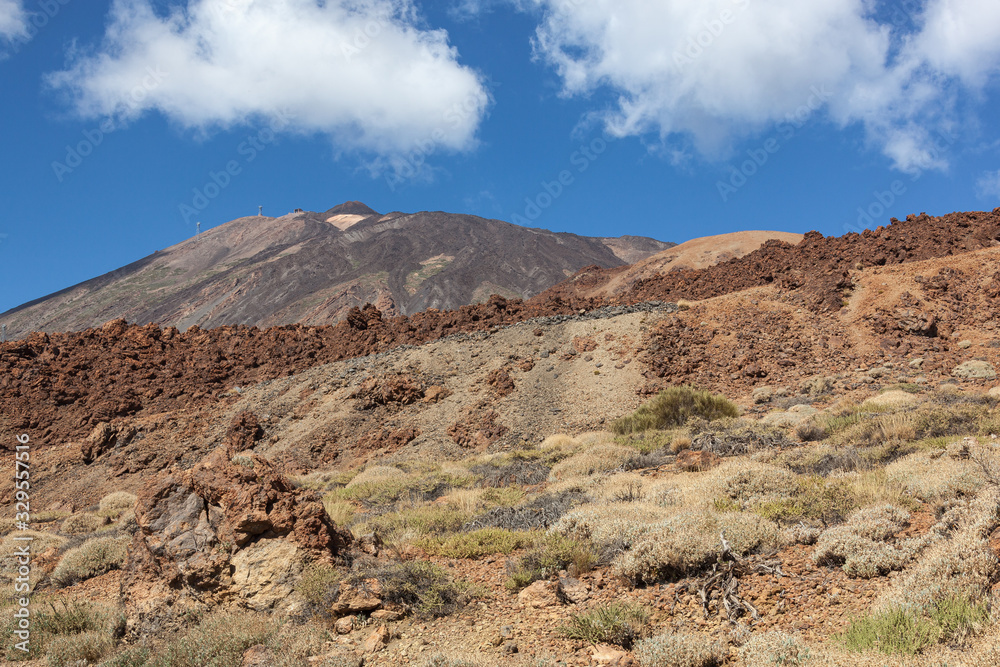 Majestic red volcanic terrain in the Teide national park with Teide Mount on the blue sky background in Tenerife, Canary Islands, Spain