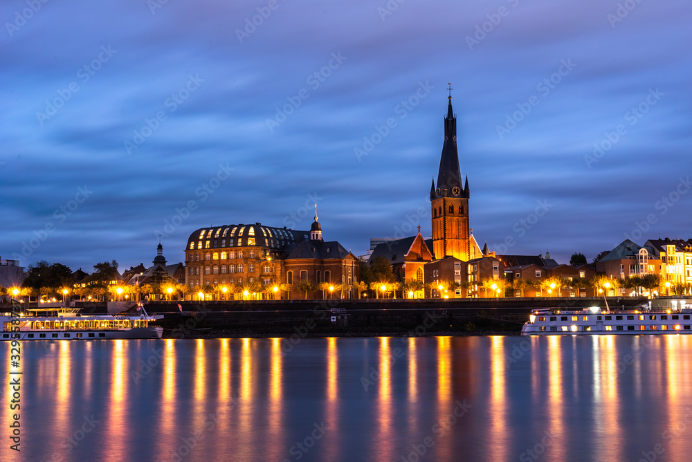 Cruise ship in the river and Saint Lambertus Catholic Church; night view of Dusseldorf on the bank of Rhine in Germany