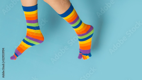 Funny playful woman legs wearing colorful socks over blue background 