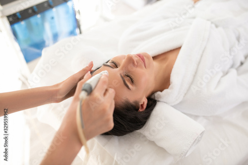 Dark-haired woman laying on the couch having rejuvenation procedures