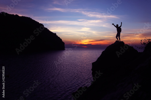 Silhouette of photographer using camera on the top of a rock by the sea , Twilight sky sunset