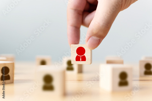 Tableau sur toile Hand of a businessman chooses a wooden cube block with icon people standing out from the crowd