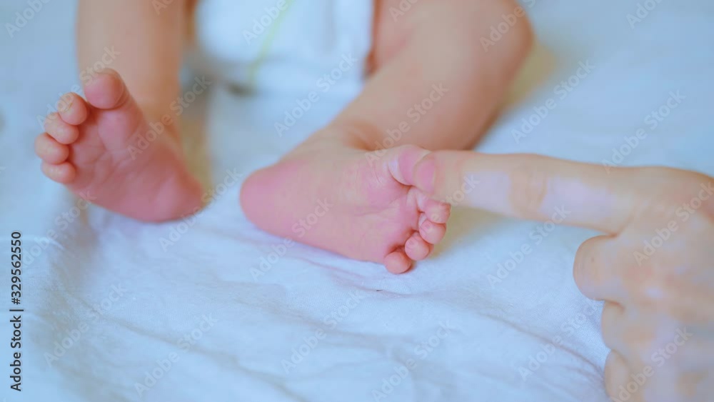 Mother strokes her newborn baby's feet. Concept of caring for children and parental love Mother strokes her newborn baby's feet. Concept of caring for children and parental love
