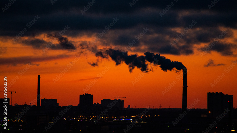 Sunset over a city with smoking chimneys