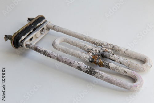 Scale and deposits on the heating element of a washing machine on a white background
