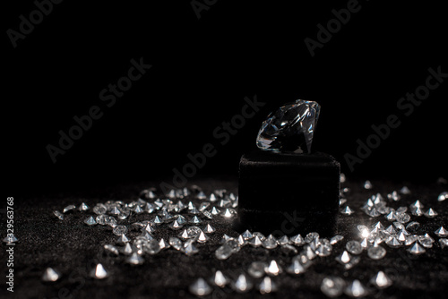 Diamond near gemstones on black velour isolated on black