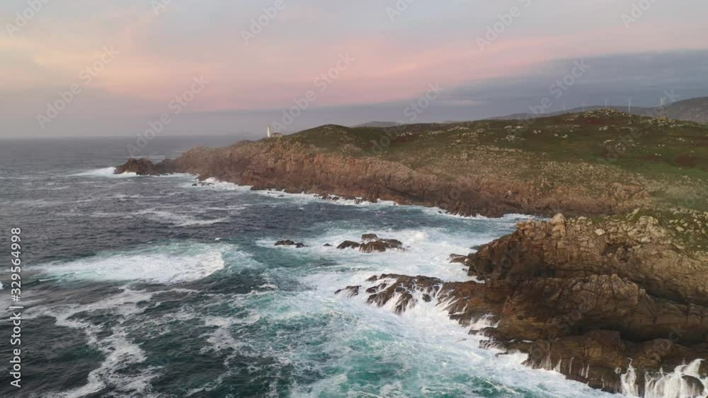 Amazing drone aerial sea landscape view of Cape Tourinan Lighthouse at sunset with pink clouds, in Spain