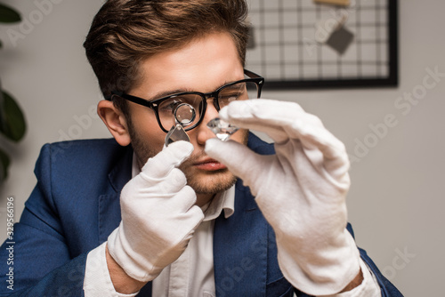 Jewelry appraiser with magnifying glass examining gemstone in workshop photo