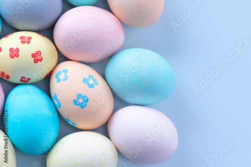 Colorful Easter eggs dyed by colored water with beautiful pattern on a pale blue background  design concept of holiday activity  top view  copy space.