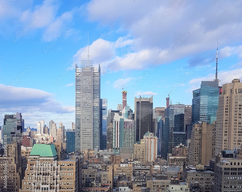 Fototapeta premium New York City cityscape with tall buildings, beautiful blue sky with clouds