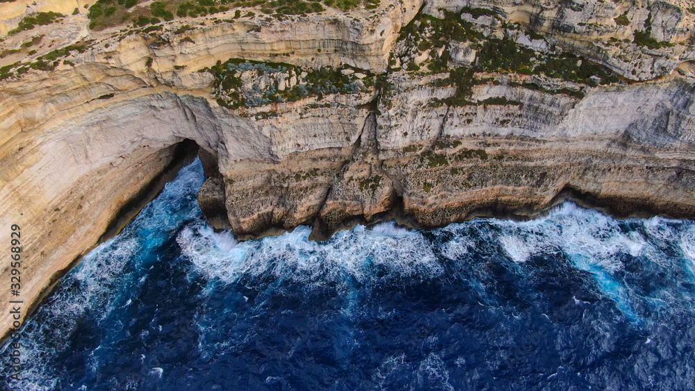 Naklejka premium Wild water hitting against the coast of Gozo Malta - top down view - aerial photography