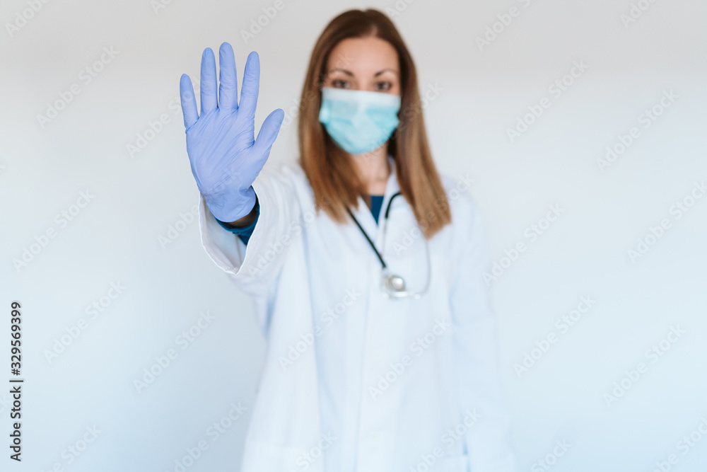 portrait of doctor woman wearing protective mask and gloves indoors. Making a stop sign with hand. Corona virus concept portrait of doctor woman wearing protective mask and gloves indoors. Making a stop sign with hand. Corona virus concept