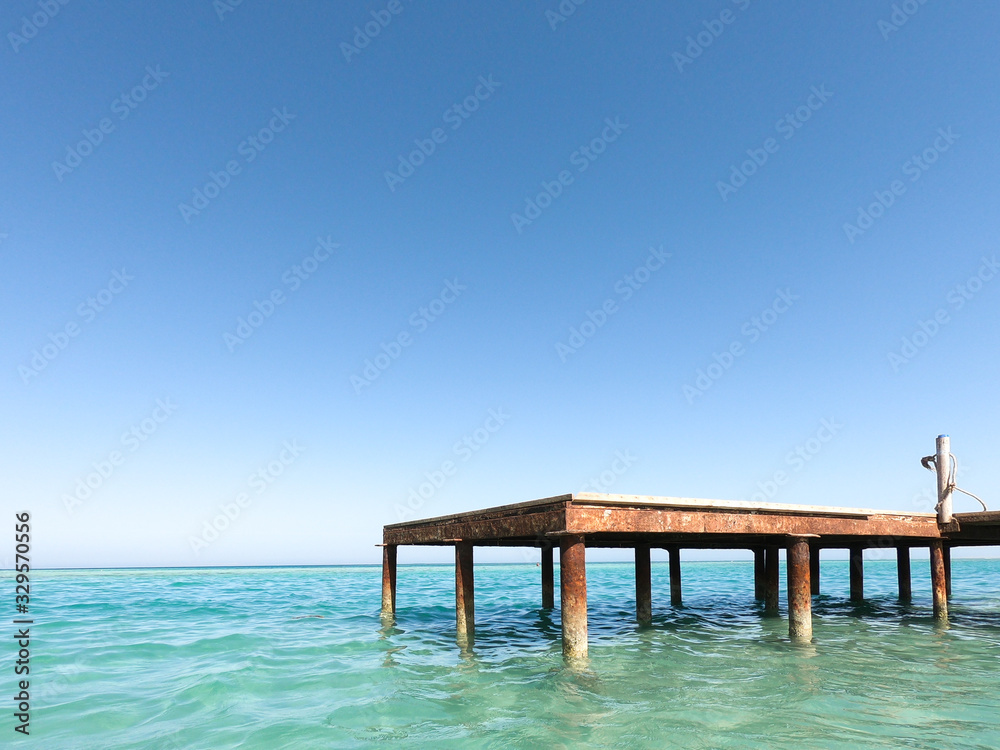 Blue sky and sea, ocean. A fabulous paradise. Jetty pier on the ocean. Wooden beams in the water. Blue horizon Rest or travel to the sea.