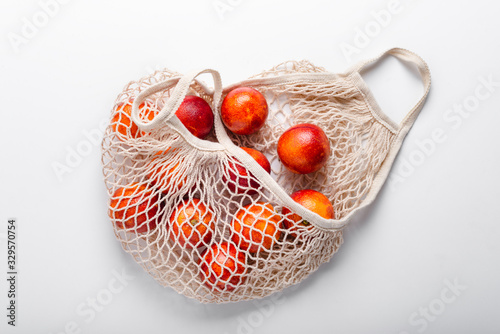 Fresh blood oranges in cotton string bag, top view