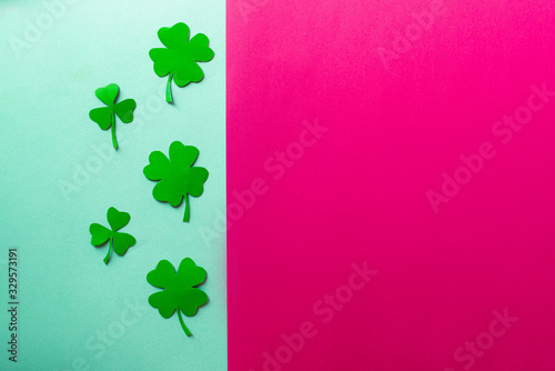 Five green clovers on a blue and rose background, flat lay, copy text, vertical separation.