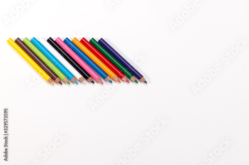 twelve small and slim colorful pencils with sharp ends on a white background