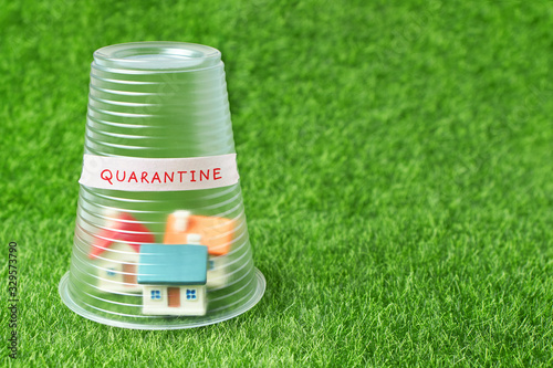 Coronavirus quarantine concept. Small house covered with transparent plastic cup and inscription Quarantine