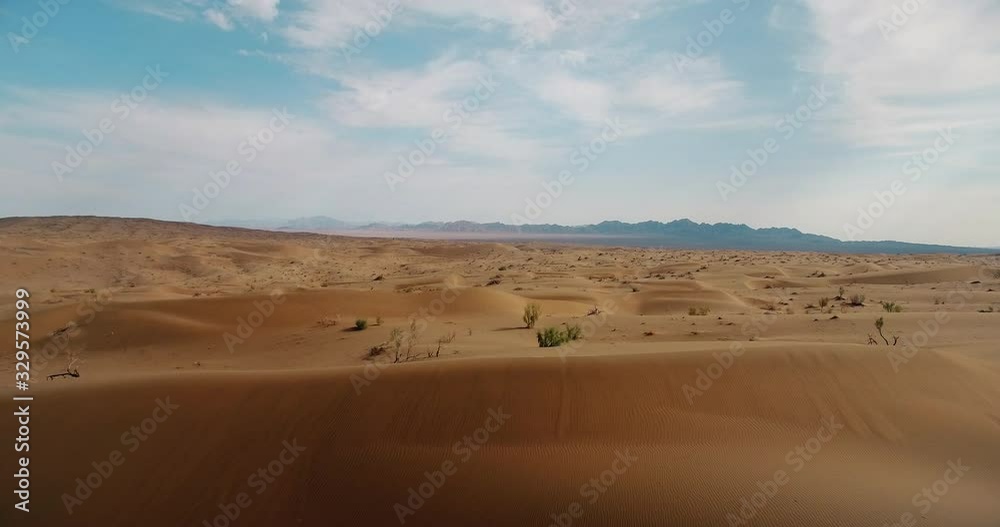 Endless desert sand dunes view all covered by sands Aerial forward shot of empty extended desert and sandy hills and plants no water just sands under blue sky natural sun light Endless desert sand dunes view all covered by sands Aerial forward shot of empty extended desert and sandy hills and plants no water just sands under blue sky natural sun light